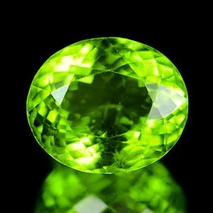 Ovaler Peridot mit hellen und dunklen Facetten vor schwarzem Hintergrund